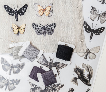 
Embroidery in process with sewing threads on table. Embroidered butterflies.