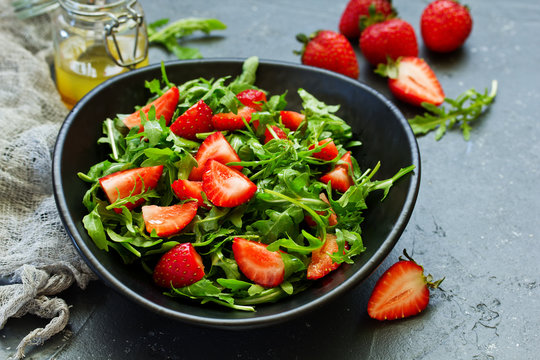 Fresh salad with arugula, strawberries and almonds. Selective focus.