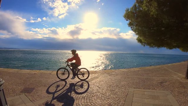 Girl riding her bicycle on a walkway by the ocean