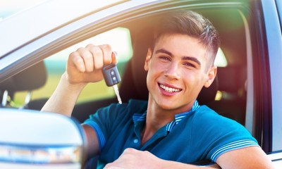 Young happy man with keys in car