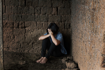 young homeless despair child, little girl sitting on floor against old earth brick wall,children...