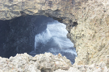 Beautiful waves and sea foam crashing in a cave boulder