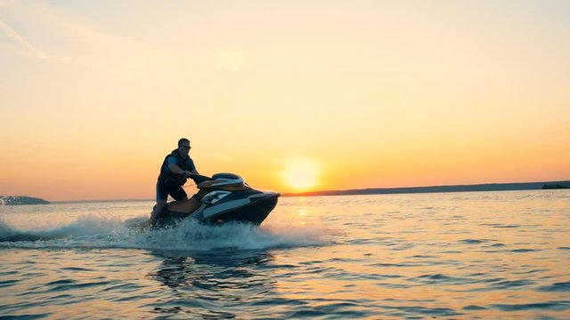 Professional jetskier is crossing open waters at the sunset