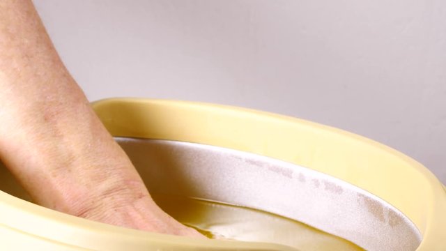 Close up slow motion shot of unrecognizable woman putting hand into paraffin bath taking care of hands skin