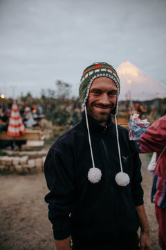 L&auml;chelnder Mann mit Bart tr&auml;gt eine bunte peruanische Wollm&uuml;tze cap to keep warm at a outdoors music festival