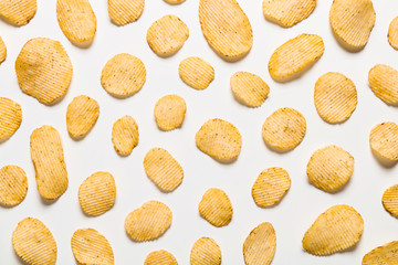 Crispy potatoes chips isolated on white background. Food background. Potato chips lying at a distance from each other on a white table.