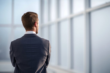rear view.businessman standing near the office window
