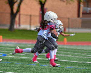 Little boys and girls playing youth tackle football