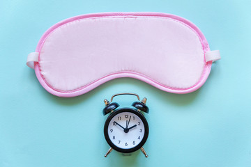 Sleeping eye mask, alarm clock isolated on blue pastel colourful trendy background. Do not disturb me, let me sleep. Rest, good night, siesta, insomnia, relaxation, tired, travel concept