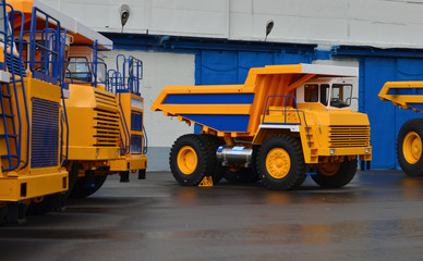 No focus. Huge yellow quarry dump trucks on large wheels at the exhibition of automotive equipment. Zhodino