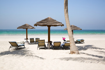 White sand beach, umbrellas, chair and turquoise water of Indean ocean, vacation and relaxing concept.