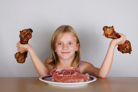 carnivore keto diet concept - little blond girl  eating raw meat   