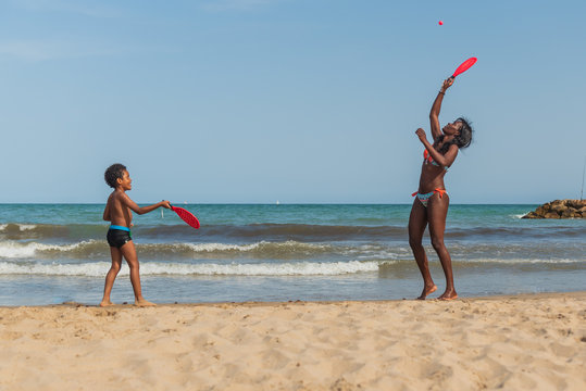 Mother And Black Son Playing Tennis On The Beach