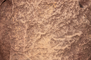 Weathered yellow stone surface, top view photo. Uneven rough texture of natural stone. Grungy stone closeup