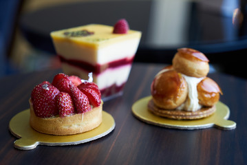Breakfast time with cup of hot coffee and pieces of cream cake with strawberries and raspberries, sweets dessert breakfast snacks, close-up. Berry cupcakes dessert on wooden table background, top view