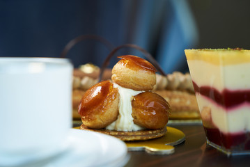 Breakfast time with cup of hot coffee and pieces of cream cake with strawberries and raspberries, sweets dessert breakfast snacks, close-up. Berry cupcakes dessert on wooden table background