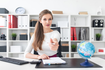 A young girl sits at the table and stretches forward the handle. Photo with depth of field, highlighted focus on the girl.