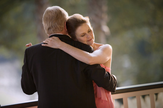Mature adult couple dressed formally and dancing on a verandah of a restaurant.