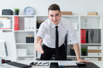 Fototapeta premium The young man in the office stands up and stretches his hand forward.