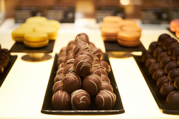 Assorted chocolate candies in a pastry shop, close-up. White chocolate nuts candy balls and macaroons, sweets dessert food 