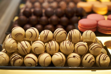 Assorted chocolate candies in a pastry shop, close-up. White chocolate nuts candy balls and macaroons, sweets dessert food 