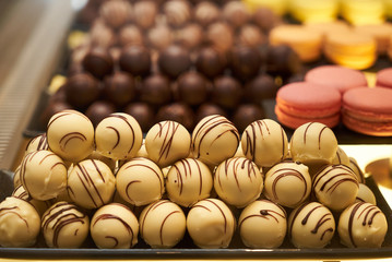 Assorted chocolate candies in a pastry shop, close-up. White chocolate nuts candy balls and macaroons, sweets dessert food 