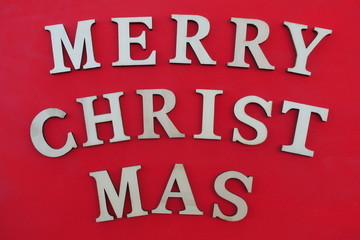 Merry Christmas text with wooden letters over red painted wooden board