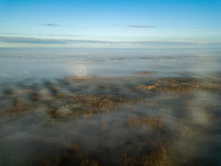 drone image. aerial view of rural area with sun halo above mist