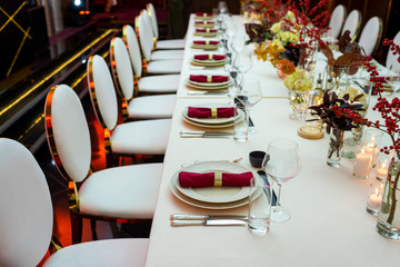 perspective decorated table in a restaurant with plates and napkins and wine glasses decorated with flowers