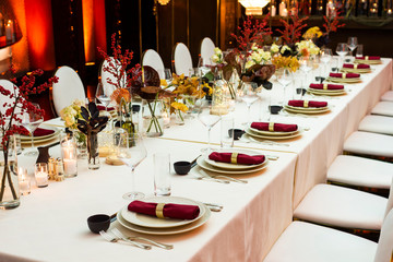 a table set for a big celebration in the evening in a restaurant decorated with flowers and candles
