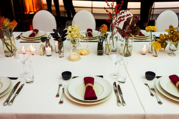 table setting in a restaurant decorated with napkins on plates and flowers and candles