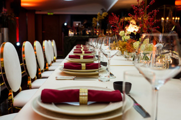 a table set for a big celebration in the evening in a restaurant decorated with flowers and candles