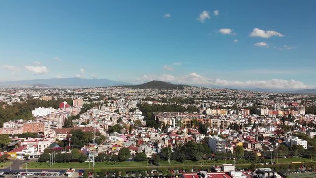Aerial panoramic view in Mexico City, with views of Cerro de la Estrella on a very clear day with blue sky. Drone flying backwards