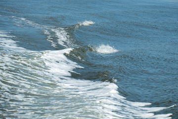 WAKE - WHITE FOAM WATER FROM A BOAT IN BLUE SEA