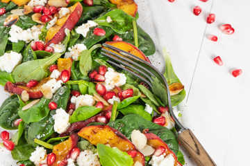 Salad. Spring vegetable salad. Fresh vegetable salad with grilled peach, pomegranate, spinach and fresh cheese