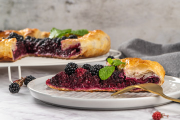 Blackberries pie with a slice on plate. Pie in summer with fresh picked wild blackberries.