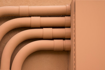 PATTERN OF PARALLEL PIPES WITH 90 DEGREE TURN TO STEEL JUNCTION BOX ON CEMENT WALL