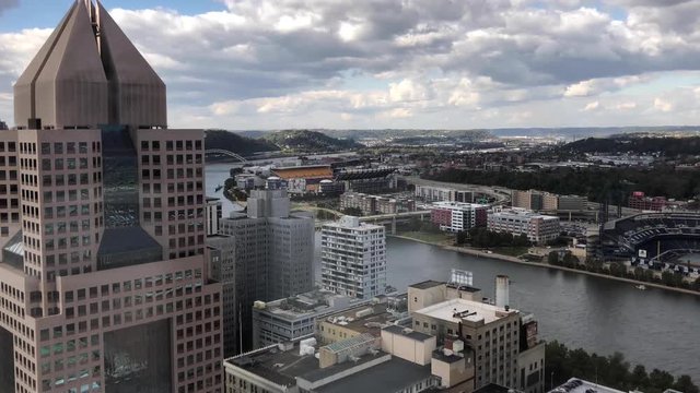 A high angle timelapse view of the downtown area of Pittsburgh, Pennsylvania on an early Autumn day. PNC Park, Heinz Field, and the Allegheny River is in the distance.  	