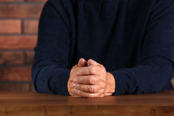 Poor elderly woman sitting at table, focus on hands