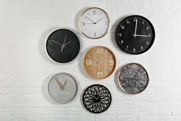 Different analog clocks hanging on white wall. Time of day