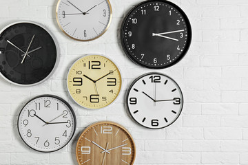 Different analog clocks hanging on white wall. Time of day