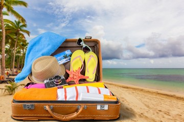 Retro suitcase with travel objects on wooden desk in beach