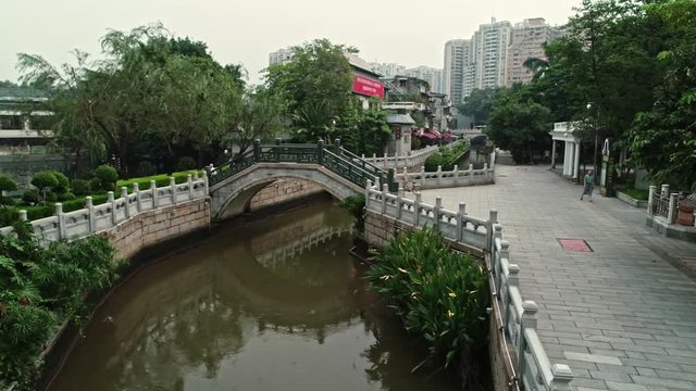 Liwan is the original city of Guangzhou, comprises old buildings and a canal system. Fly through and over the canal and see Liwan natural park, daylight, 4k, d-log, b-roll