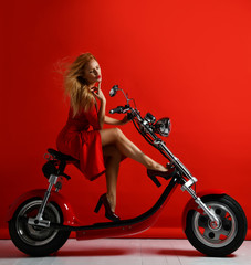 Fototapeta na wymiar Woman ride new electric car motorcycle bicycle scooter present for new year in red dress 