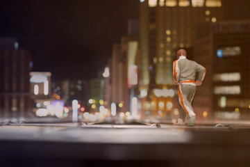 MINIATURE RUNNER RUNS ON DART BOARD TOWARD BOKEH LIGHT OF BUSY TOWN AT NIGHT, HOKKAIDO / JAPAN. HEALTH LIFESTYLE & SUCCESS CONCEPT