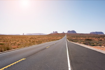 STRAIGHT ASPHALT ROAD WITH YELLOW LINE ON THE WAY TO MONUMENT VALLEY, ARIZONA-UTAH BORDER, USA