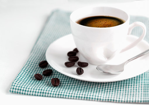 A cup of white coffee and saucer are placed on a bright green cloth.  Copy space for text or image.