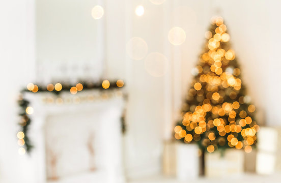 Holiday decorated room with Christmas tree and decoration, backgroound with blurred, sparking, glowing light.