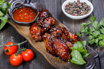Barbecue chicken wings with bbq sauce on plate on wooden background. Hot Meat Dishes