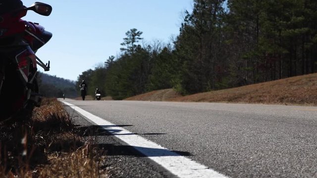 Motorcycles doing wheelies on a country road.